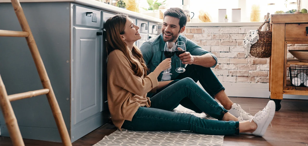 Junges Paar sitzt in der Küche auf einem Teppich mit einem Glas Wein - Junges Paar sitzt in der Küche auf einem Teppich mit einem Glas Wein