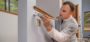 Professionelle kommerzielle, Anstreicher, Wand Malerei mit Pinsel drinnen im Zimmer des Hauses